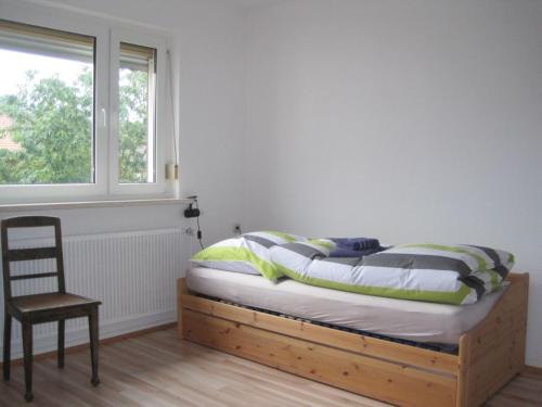 1 dormitorio con 1 cama con silla y ventana en Haus-Dorfidyll, en Spangenberg
