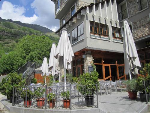 un hotel con mesas y sombrillas blancas delante en Hostal Pey, en Bohí