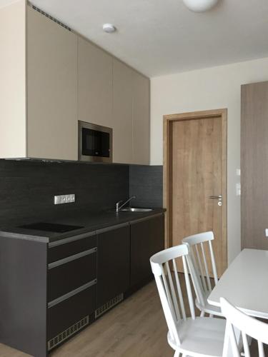 ドルニー・モラヴァにあるZlatý Apartmánのキッチン(黒いカウンター、白い椅子付)