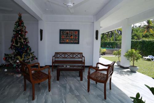 a christmas tree in a living room with two chairs and a christmas tree at Athithi Villa in Hikkaduwa