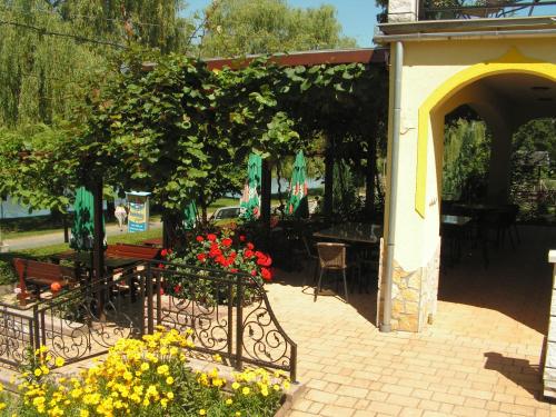 a patio with a table and chairs and flowers at Nefelejcs Fagyizó és Apartmanház in Kistolmács