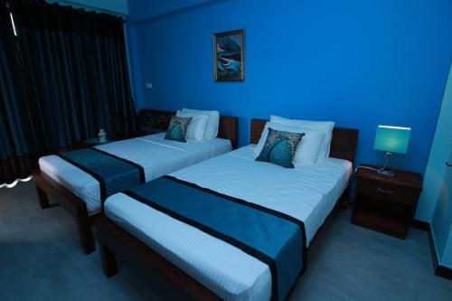 two beds in a room with blue lighting at Athithi Villa in Hikkaduwa