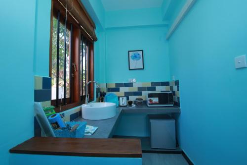a kitchen with a sink and a blue wall at Athithi Villa in Hikkaduwa
