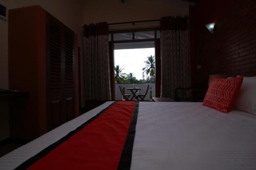 a bedroom with a bed with a red and white blanket at Athithi Villa in Hikkaduwa