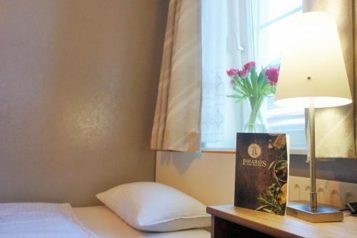 a bedroom with a bed and a window with a vase of flowers at Pharos zur Seeve in Seevetal