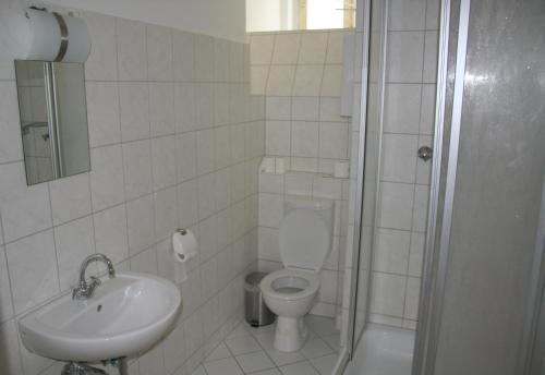 a bathroom with a toilet and a sink and a shower at City Hotel Gotland in Berlin