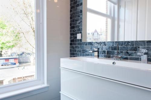 łazienka z białą umywalką i oknem w obiekcie Da Costa Suite w Amsterdamie