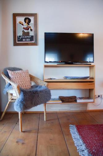 a living room with a flat screen tv and a chair at Landlust Ischl in Bad Ischl