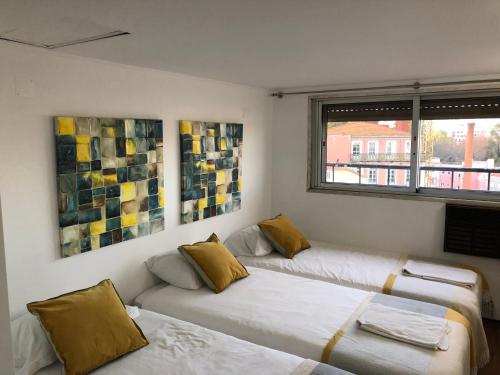 リスボンにあるPrincipe Real Duplex - 3 Bedroomの壁に絵画が飾られた客室内のベッド2台