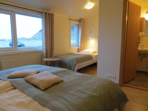 Cette chambre comprend deux lits et une grande fenêtre. dans l'établissement Guesthouse Vellir, à Vík