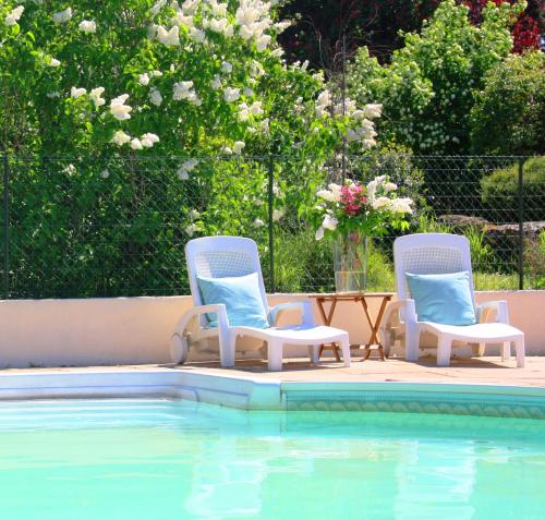 two chairs and a table next to a swimming pool at Domaine Charente Glamping Familyroom Le Jardin with external toilet & shower house & outdoor kitchen in Mazières