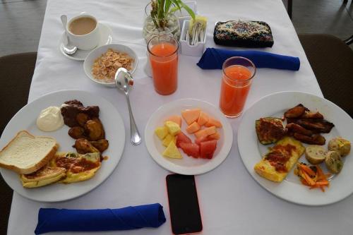 a white table with plates of breakfast foods and drinks at Hotel Latitud 15 in San Pedro Sula