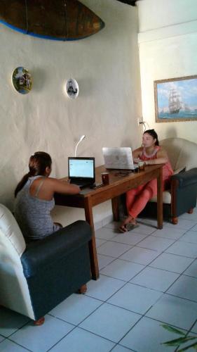 two women sitting at a table with their laptops at Lorena Surf Hostel in San Juan del Sur