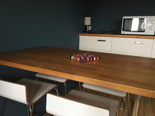 a wooden table with chairs and a microwave at Les Jardins de l'Ile in Longeville-lès-Metz