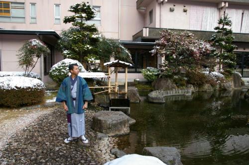 a man standing next to a pond in a garden at Bosenkan in Gero