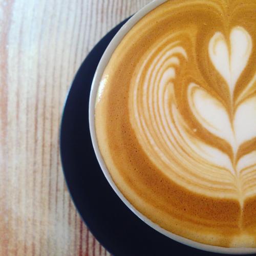 a cup of coffee with a heart painted on it at Ten Dollar Town Motel in Gulgong
