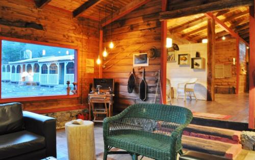 a living room with a green chair in a wooden house at Las Pitras Lodge in Epuyén