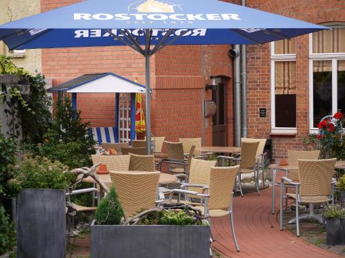 a patio with tables and chairs and an umbrella at Restaurant & Hotel Wismar in Wismar