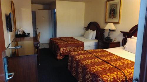 a hotel room with two beds and a television at Valley Hotel in Rosemead
