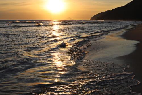 a sunset on the beach with the tide coming in at Casa Ka in Maresias