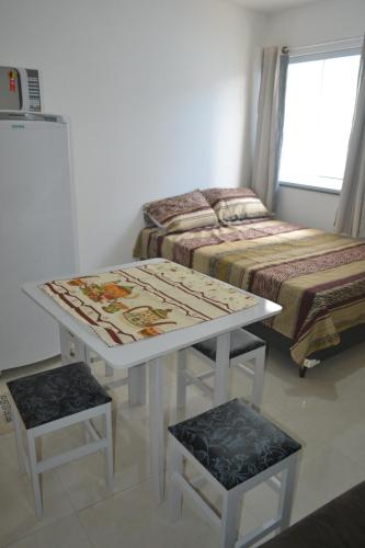 mesa blanca y taburete en una habitación con cama en Loft Centro, en Arraial do Cabo