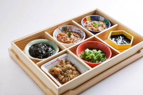 a wooden tray filled with different types of food at Almont Hotel Naha Kenchomae in Naha