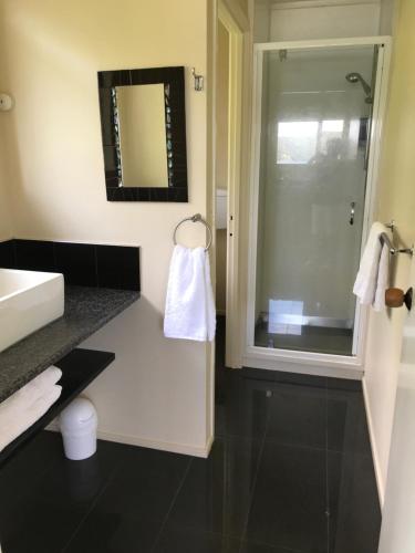 a bathroom with a sink and a shower with a mirror at Tipi and Bobs Waterfront Lodge in Tryphena