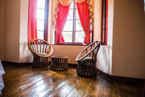 three chairs in front of a window with red curtains at Royal Majesty Bungalow in Hatton