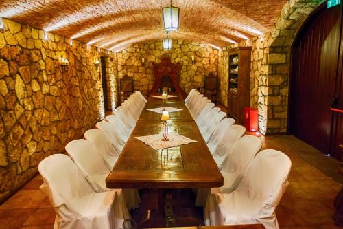 a long table and white chairs in a stone room at Estate Kalaitzis in Vergina