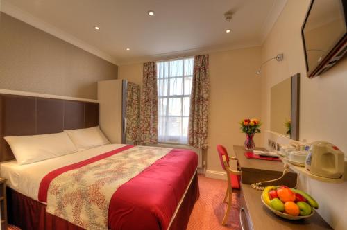 a hotel room with a bed and a table with a bowl of fruit at Best Western Buckingham Palace Rd in London