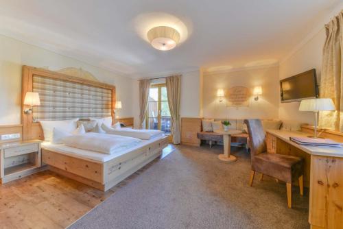 ein Schlafzimmer mit einem Bett und einem Schreibtisch mit einem Computer in der Unterkunft Posthotel Hofherr in Königsdorf