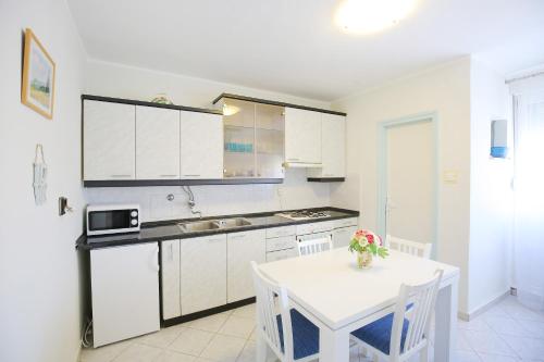 una cucina con armadi bianchi, tavolo bianco, tavolo e tavolo bianco di Good Vibes Apartment a Zara (Zadar)