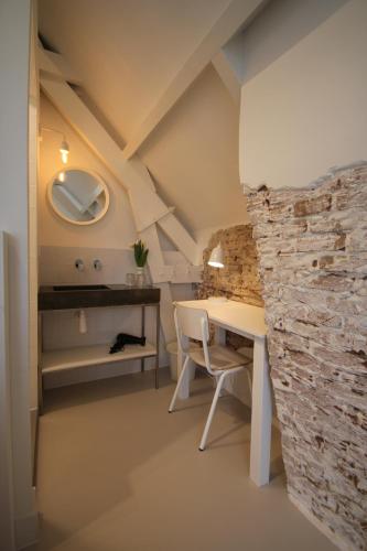 a room with a table and a stone wall at Het Spoorhuis Uithoorn in Uithoorn
