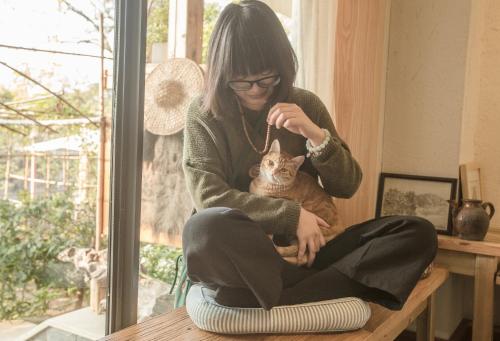 a woman sitting on a table holding a cat at Zen Tea House Seven Stars Park in Guilin