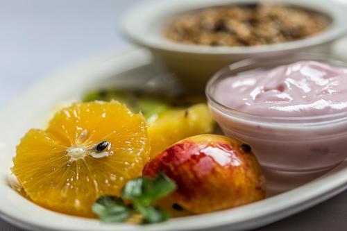 a white plate with fruit and a bowl of sauce at Wendy's Country Lodge in Mtubatuba