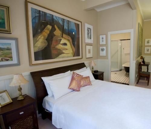 a bedroom with a white bed and a painting on the wall at The Chalet Guesthouse And Studio in Medlow Bath