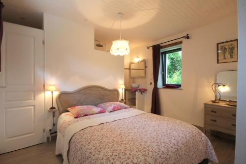 een slaapkamer met een bed met 2 kussens en een raam bij Les Herbagettes in Nonant