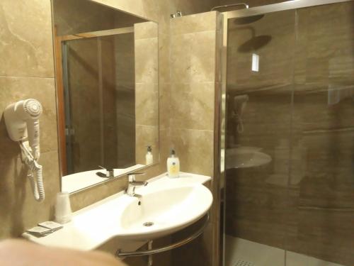 a bathroom with a sink and a shower with a mirror at Hotel Yeste in Yeste