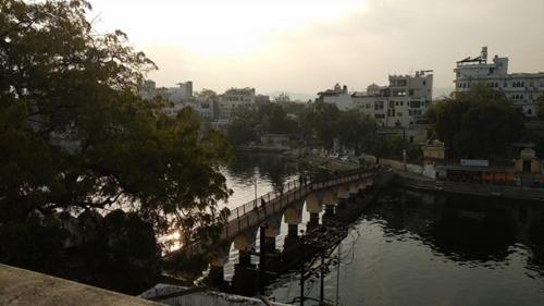 a bridge over a river in a city with buildings at Bagol Palace in Udaipur