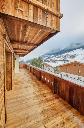 a wooden deck with a view of the snow covered mountains at Chalet Guter Hirte in Saalbach Hinterglemm