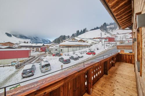 a balcony with snow covered cars parked in a town at Chalet Guter Hirte in Saalbach Hinterglemm