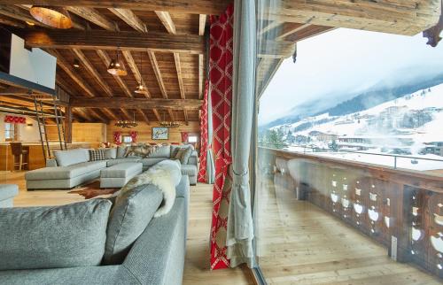 a living room with couches and a large window at Chalet Guter Hirte in Saalbach Hinterglemm