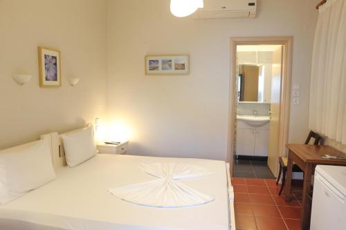 a bedroom with a white bed and a bathroom at Spyrou Studios & Apartments in Platanidia