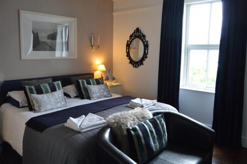 a bedroom with a bed with a chair and a mirror at The Bakehouse B&B in Seahouses