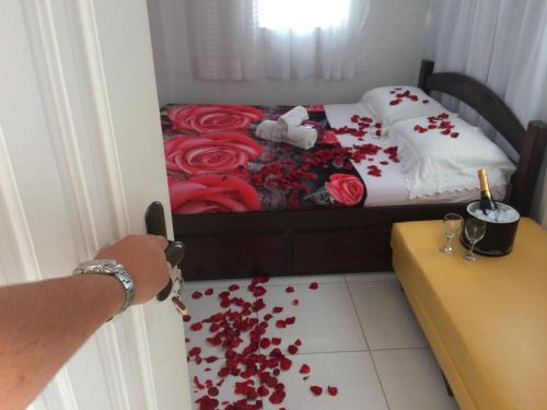 Habitación con cama con rosas rojas en el suelo en Suítes da Erô, en Arraial do Cabo