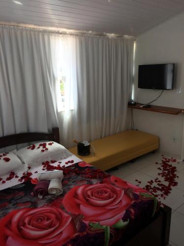 a bedroom with a bed with red roses on it at Suítes da Erô in Arraial do Cabo