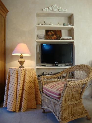 a living room with a wicker chair and a television at La Guéritaulde in La Tour-dʼAigues
