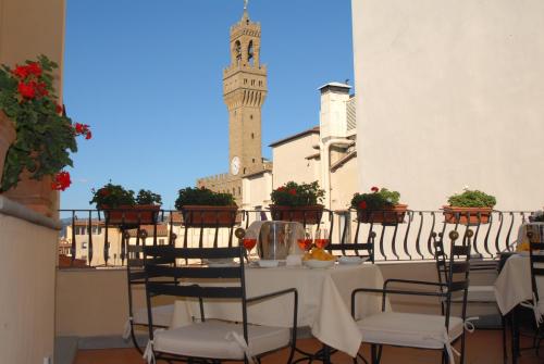 een tafel en stoelen op een balkon met een klokkentoren bij Hotel degli Orafi in Florence