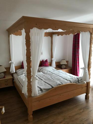 Schlafzimmer mit einem hölzernen Himmelbett mit Vorhängen in der Unterkunft Ferienwohnung Franziska 2 in Garmisch-Partenkirchen