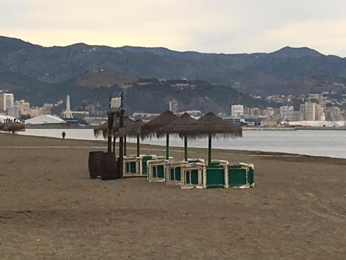 a group of umbrellas and chairs on a beach at Apartamento Paseo Marítimo Antonio Banderas in Málaga
